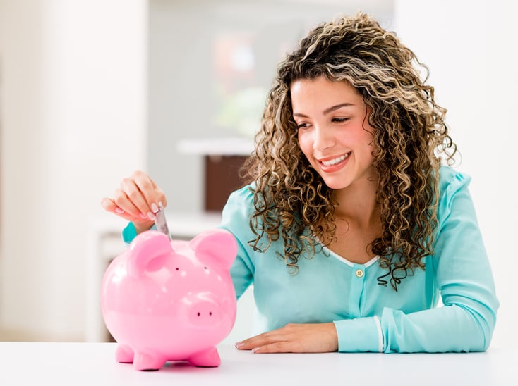 Happy woman saving money in a piggybank