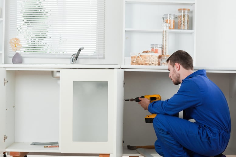 Good looking handyman fixing a door in a kitchen-3