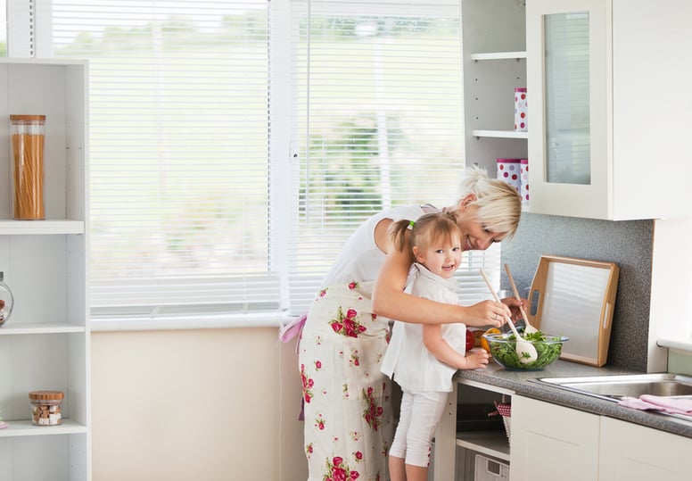 Jolly girl preparing a salad with her mother in the kitchen