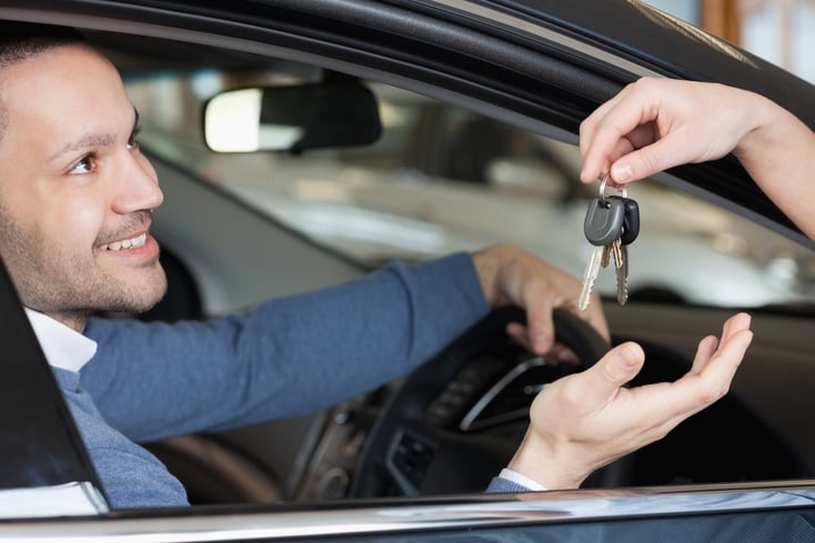 Man receiving keys while sitting in a car