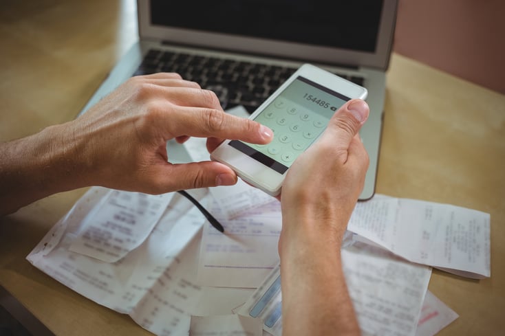 Mid section of man calculating bills on mobile phone-2