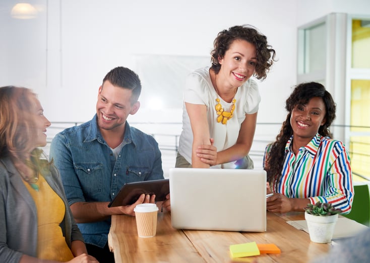 Multi ethnic group of succesful creative business people using a laptop during candid meeting