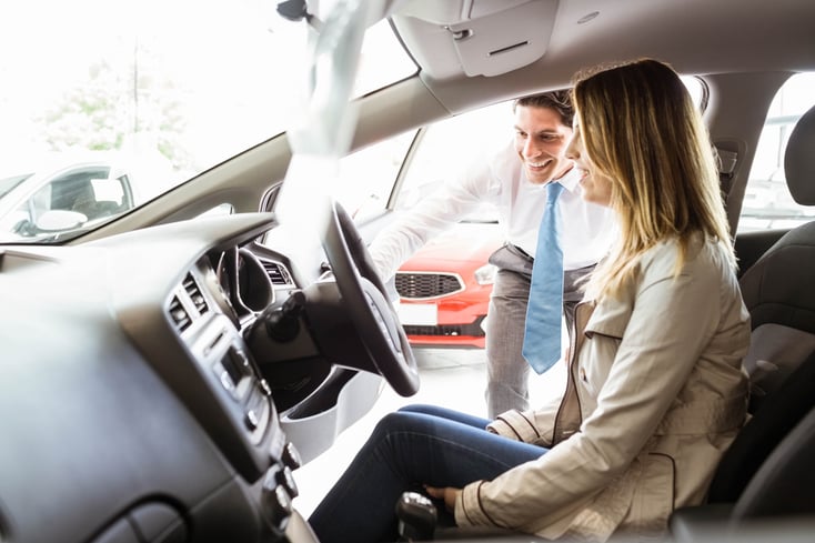 Salesman showing things to a customer at new car showroom