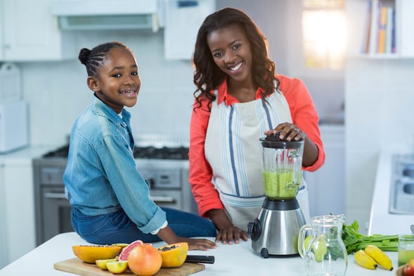 Woman and daughter using mixer in kitchen
