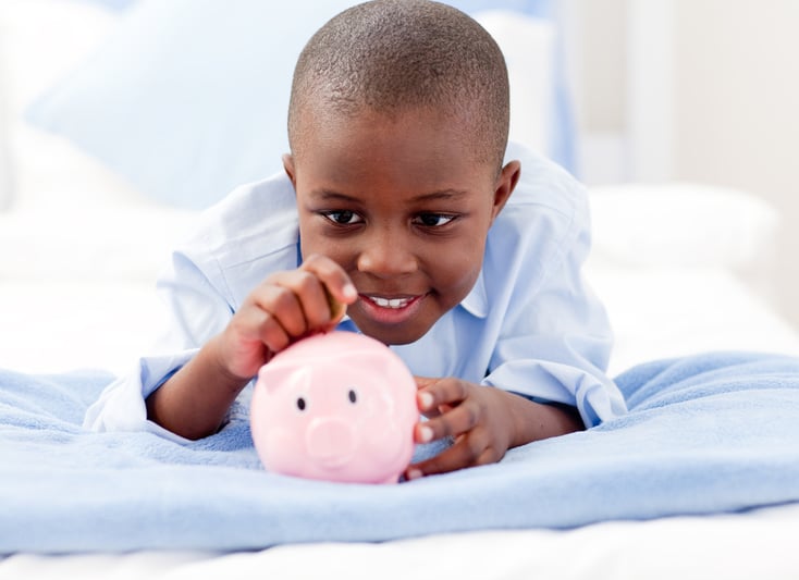 Young Boy lying on his bed putting money into a piggy bank-1