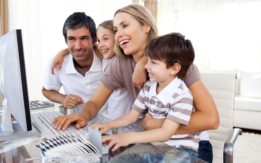 Caring parents teaching their children how to use a computer in the living-room