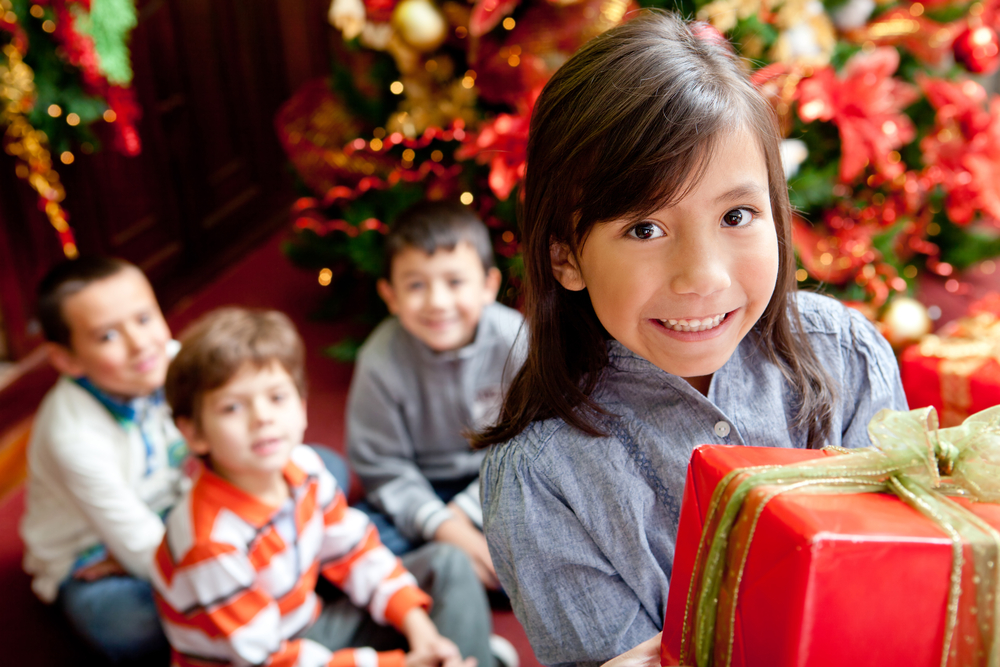 Group of children with presents next to the tree celebrating Christmas